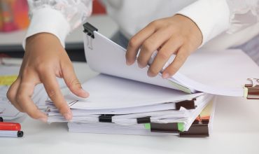 businesswoman hands working in stacks of paperwork files for sea